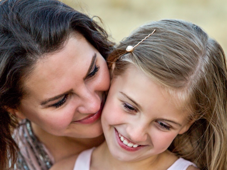 A parent and child cheek to cheek, smiling outdoors